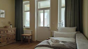 Ein Schlafzimmer mit Bett, Schminktisch, Stuhl und einem Fenster mit Vorhängen.