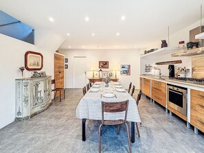 A dining room with a long table set for six, flanked by wooden cabinets and a kitchen area with modern appliances. - Kervourden by Interhome (La Trinité Sur Mer)