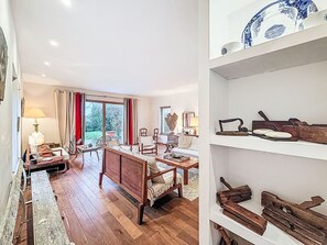 A spacious living room with a wooden floor, a dining area with a table and chairs, and a large window with curtains. - Kervourden by Interhome (La Trinité Sur Mer)