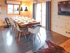 Un espace repas moderne avec une table en bois, dressée pour six personnes, entourée de chaises.