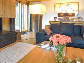 A cozy living room with a sofa, a coffee table with books and a vase of flowers, and a lamp.