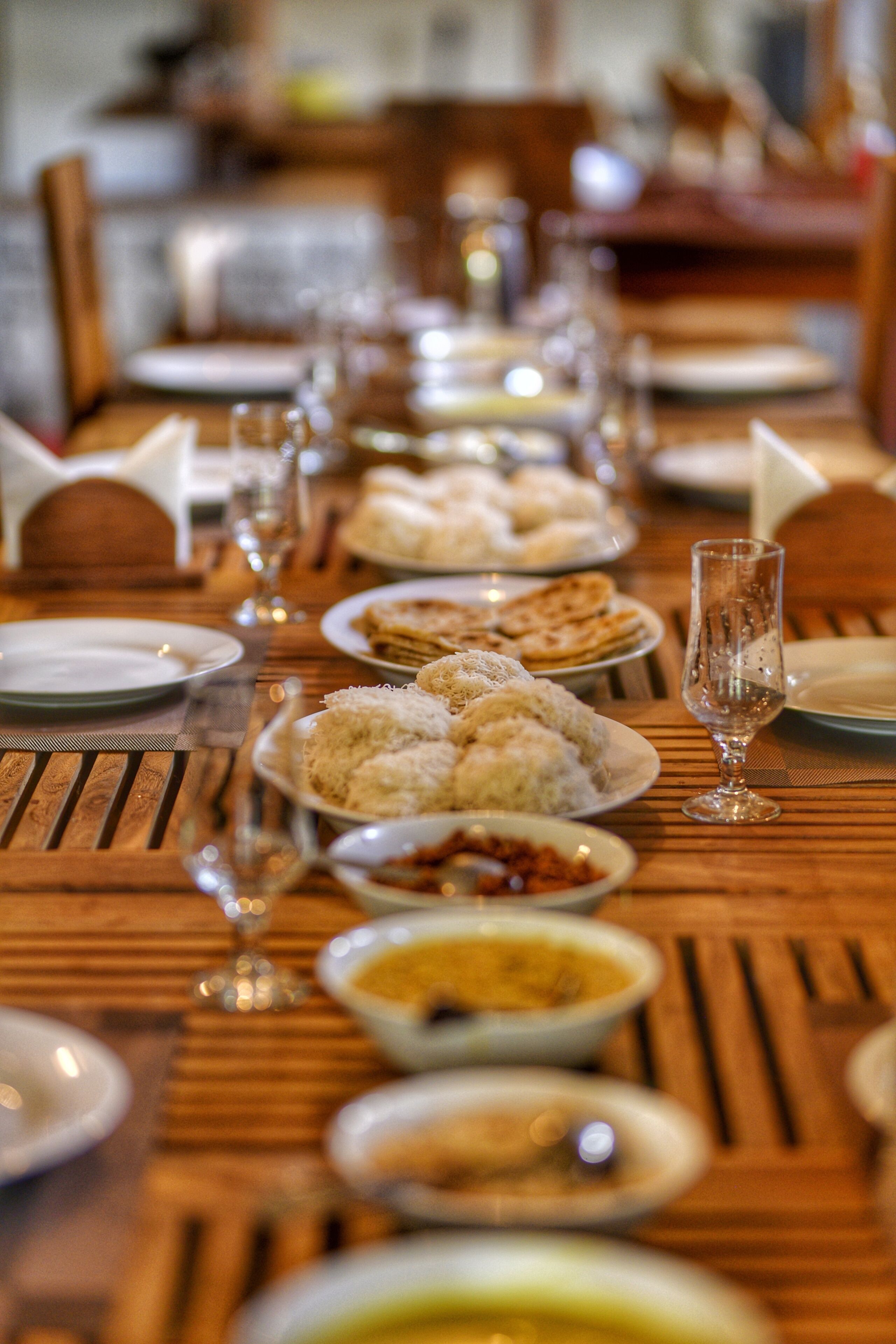 A dining table set with plates of food, glasses, and cutlery.