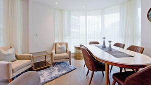 En moderne stue med sofa, lænestol og spisebord med stole.