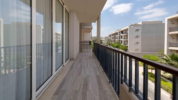 Een balkon met uitzicht op omliggende gebouwen en een heldere lucht.