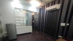 A room with a dark wooden floor, a white radiator, a grey cabinet, and a black wall with vertical stripes.