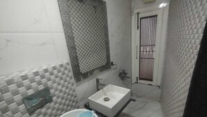 A bathroom with a white sink, a mirror, and a tiled wall.