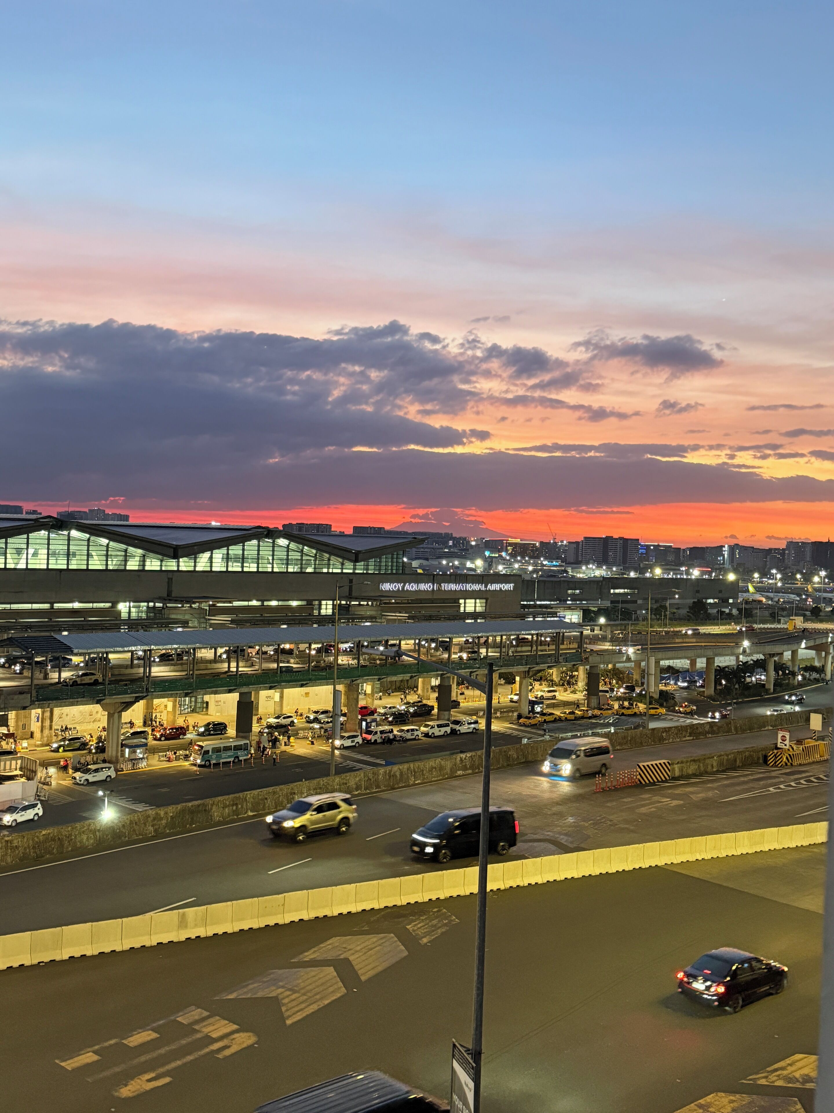 An airport terminal with multiple levels, including a rooftop area with glass railings.