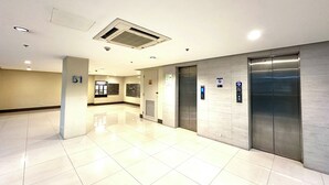 A clean, modern lobby with a tiled floor, a reception desk, and an elevator. - One Palm Tree Villas Across MNL Airport T3 (Pasay)