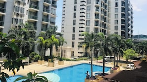 A modern residential building with multiple balconies, a swimming pool, and surrounding greenery. - One Palm Tree Villas Across MNL Airport T3 (Pasay)