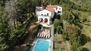 Uma villa com piscina, rodeada por vegetação exuberante e colinas.