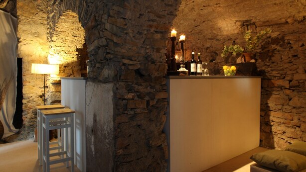 Um quarto com paredes de pedra, uma área de bar, um pequeno espaço para sentar e um abajur.