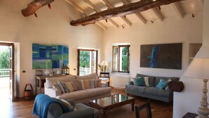 Uma sala de estar espaçosa com dois sofás, uma mesa de centro e um quadro grande.