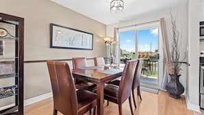 A dining area with a wooden table and leather chairs, a framed artwork on the wall, and a view through the glass door. - Cozy, Quiet Home in Kingston. Short drive to Queen's University. Pet Friendly! (Kingston)