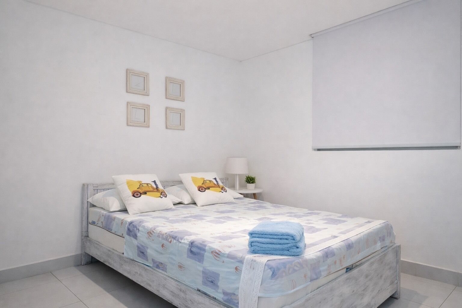 Ein Schlafzimmer mit Bett, Kissen, einem Nachttisch, einer Lampe und einem an der Wand befestigten Fernseher.