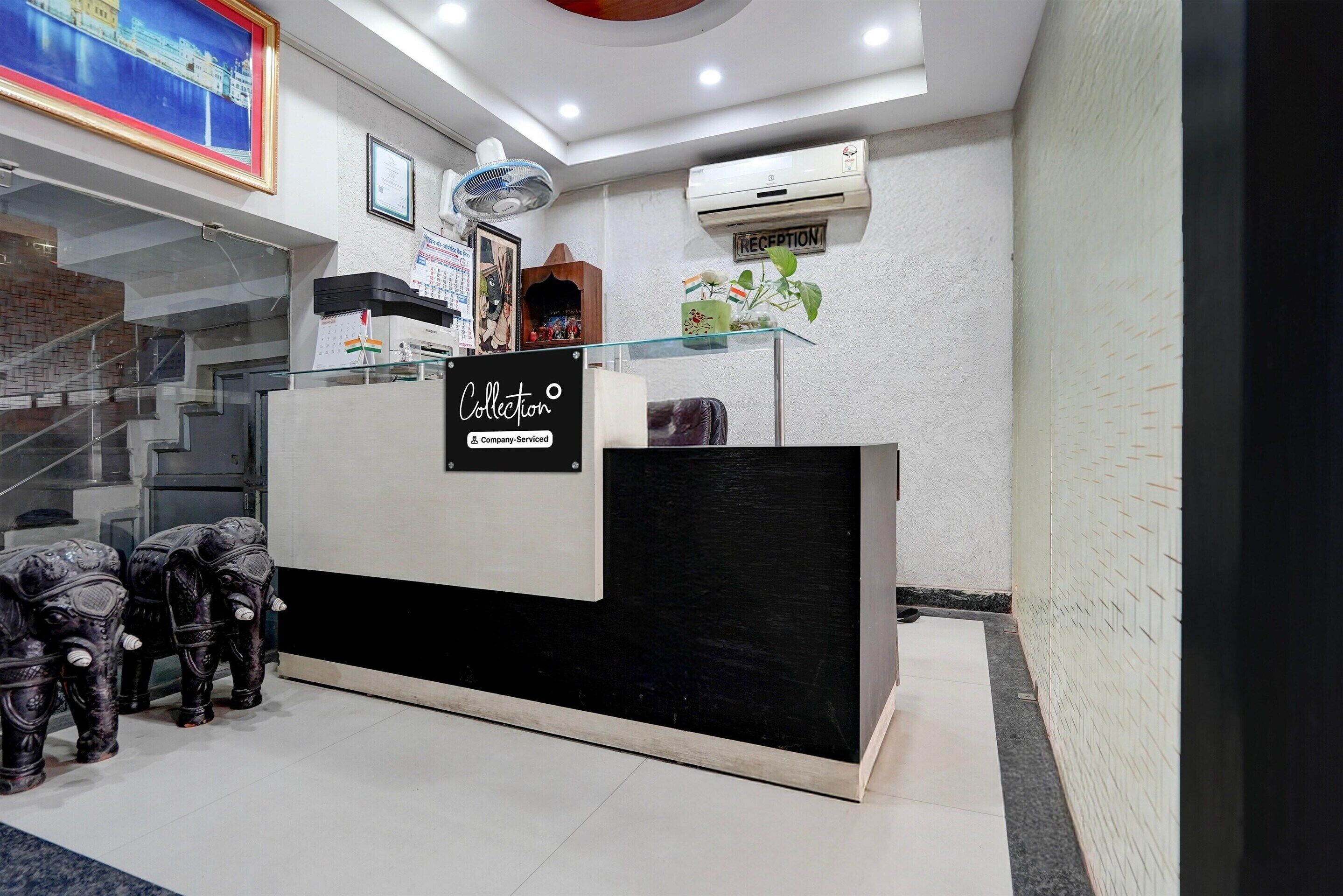 A reception desk with a glass top, a sign reading "Collection," and a staircase in the background.