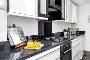A modern kitchen with white cabinets, a black countertop, and stainless steel appliances.