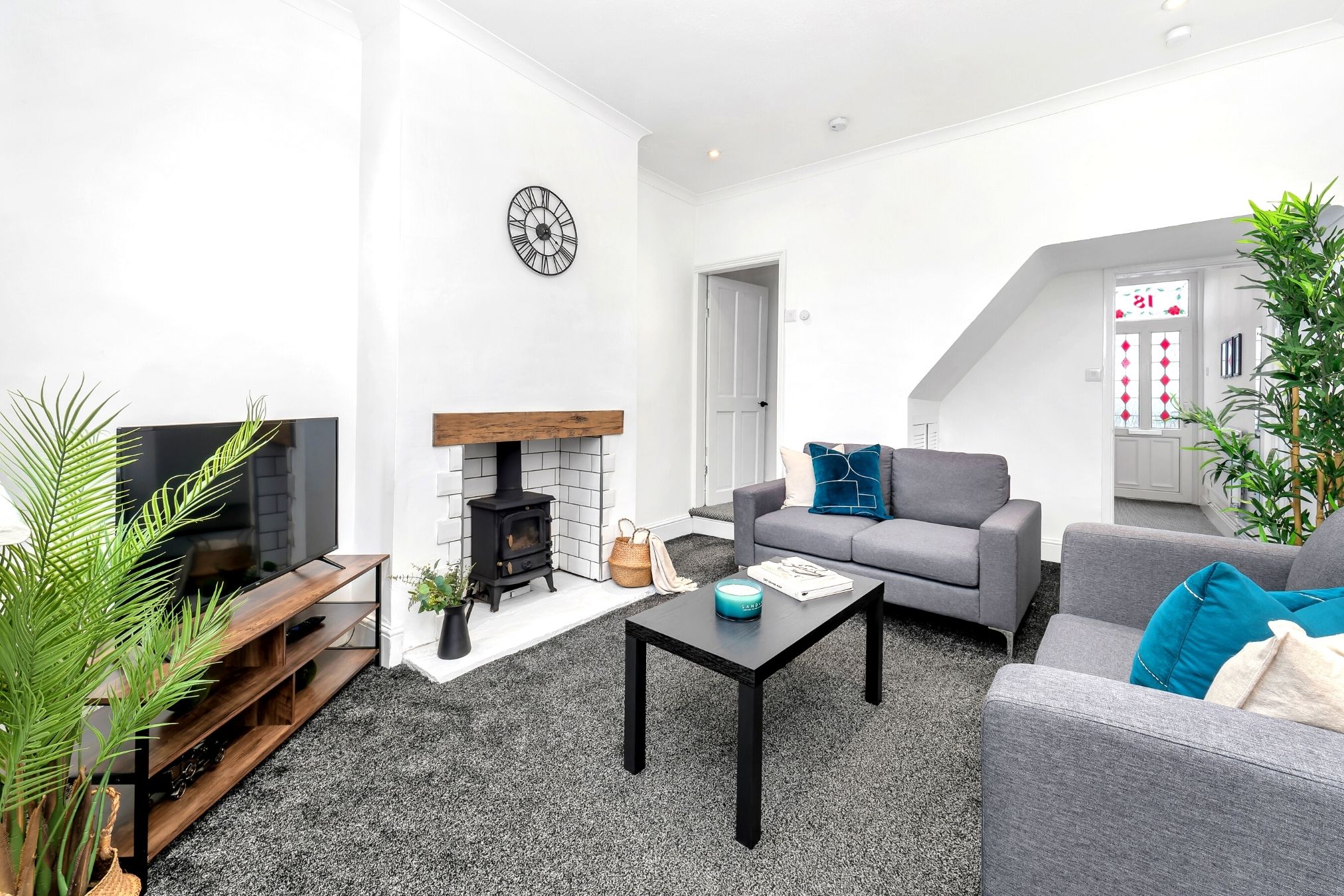 A modern living room with a fireplace, grey sofas, a coffee table, and a TV.