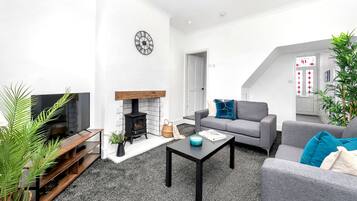 A modern living room with a fireplace, grey sofas, a coffee table, and a TV.
