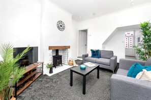 A modern living room with a fireplace, grey sofas, a coffee table, and a TV.