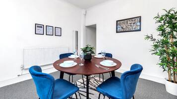 A conference room with a round table, four blue chairs, a potted plant, and framed certificates on the wall.