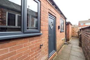 A narrow brick alleyway with a dark-colored door and windows.