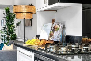 Une cuisine moderne avec une cuisinière à gaz, un magazine posé sur le comptoir et une plante.