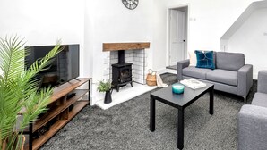 A modern living room with a fireplace, a sofa, a coffee table, and a TV.