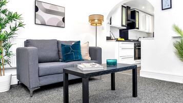 A modern living room with a grey sofa, a coffee table, and a floor lamp.