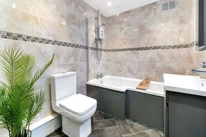 A modern bathroom with a toilet, bathtub, and shower. - Chorlton House | Free Parking | 2BR Stoke-on-Trent (Stoke-on-Trent)