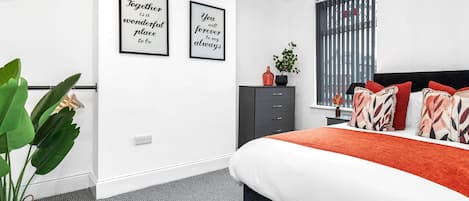 Un dormitorio moderno con una cama, un aparador y dos carteles con mensajes inspiradores en la pared.