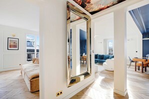 A spacious room with a large mirror, a bed, a blue sofa, and a dining area. - Beautiful Apartment - Ac-1br- 3P - Les Halles (Paris)
