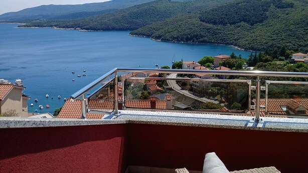 Varanda com vista para a costa, incluindo um corpo de água e colinas ao longe.