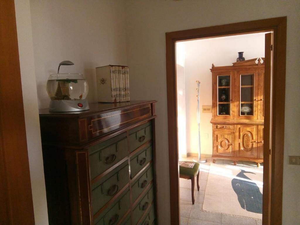 A room with a wooden cabinet, a fish tank, and a door leading to another room.