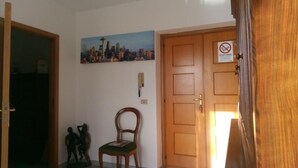 A room with a wooden door, a chair, a small statue, and a cityscape painting on the wall. - AT THE OLD STUDIO (Vibo Valentia)