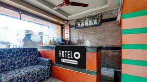 Zona de recepción de un hotel con un sofá, un mostrador y un ventilador de techo.