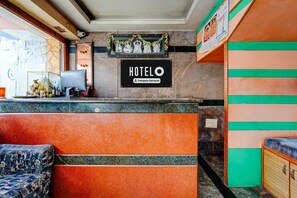 Een hotel receptie met een receptiebalie, een computer en een bordje waarop staat dat het hotel bedrijfsmatig wordt beheerd.