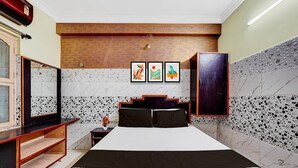 Una habitación de hotel con una cama, cabecera de madera, mesita de noche, espejo y obras de arte en la pared.