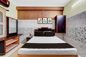 Een hotelkamer met een bed, een houten hoofdeinde, een nachtkastje, een spiegel en kunst aan de muur.
