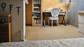 Ein Schlafzimmer mit einem gestreiften Bett, einem Schreibtisch mit Stuhl, einem Bücherregal und einer Lampe.