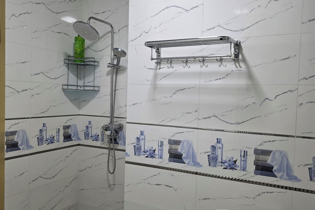 Un baño con ducha, inodoro y perchero para toallas.
