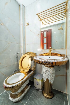 Ein Badezimmer mit Toilette, Waschbecken und Duschkopf, alles in Gold.