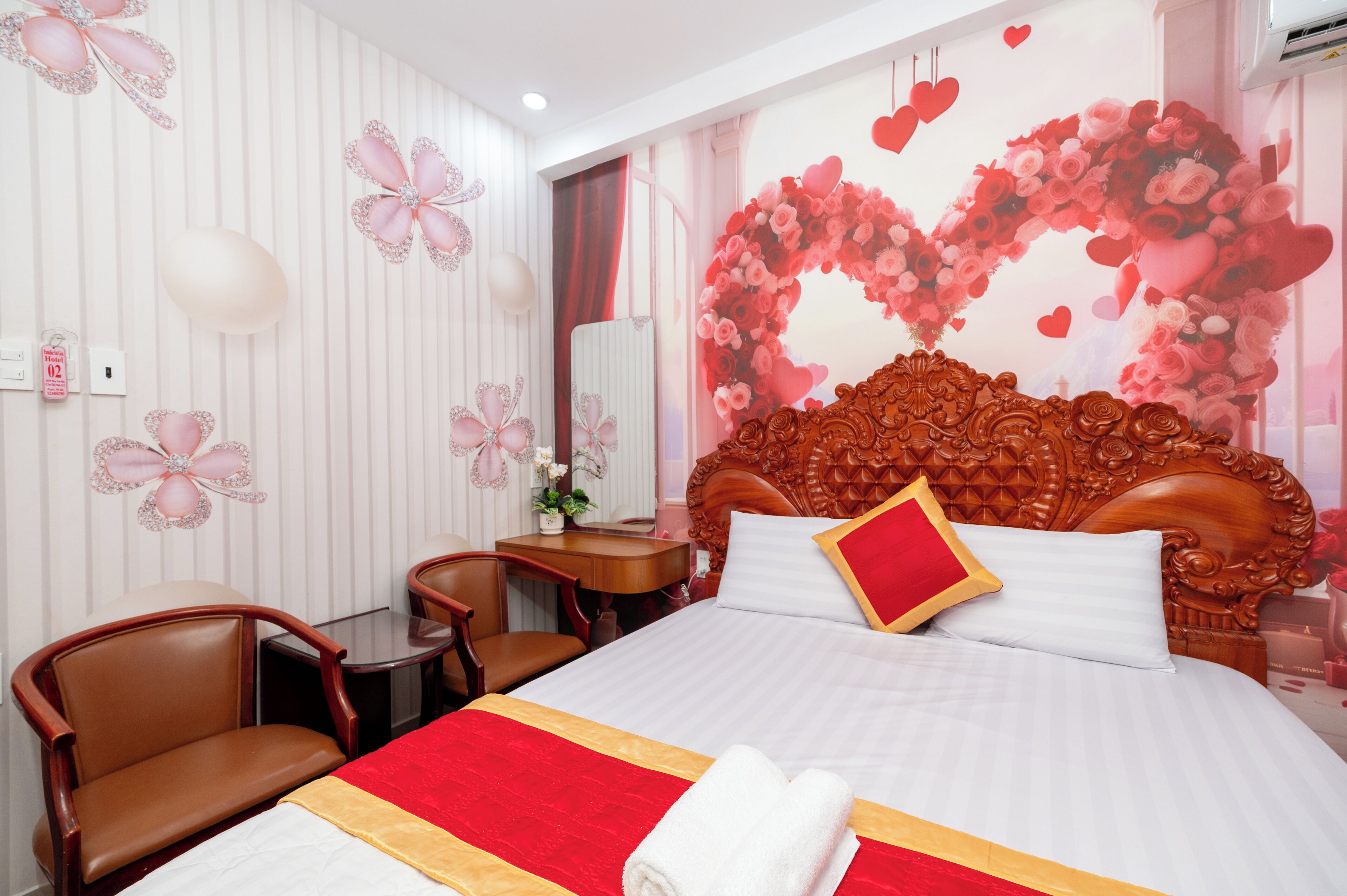 A hotel room with a large bed, a wooden headboard, a desk, and a chair.