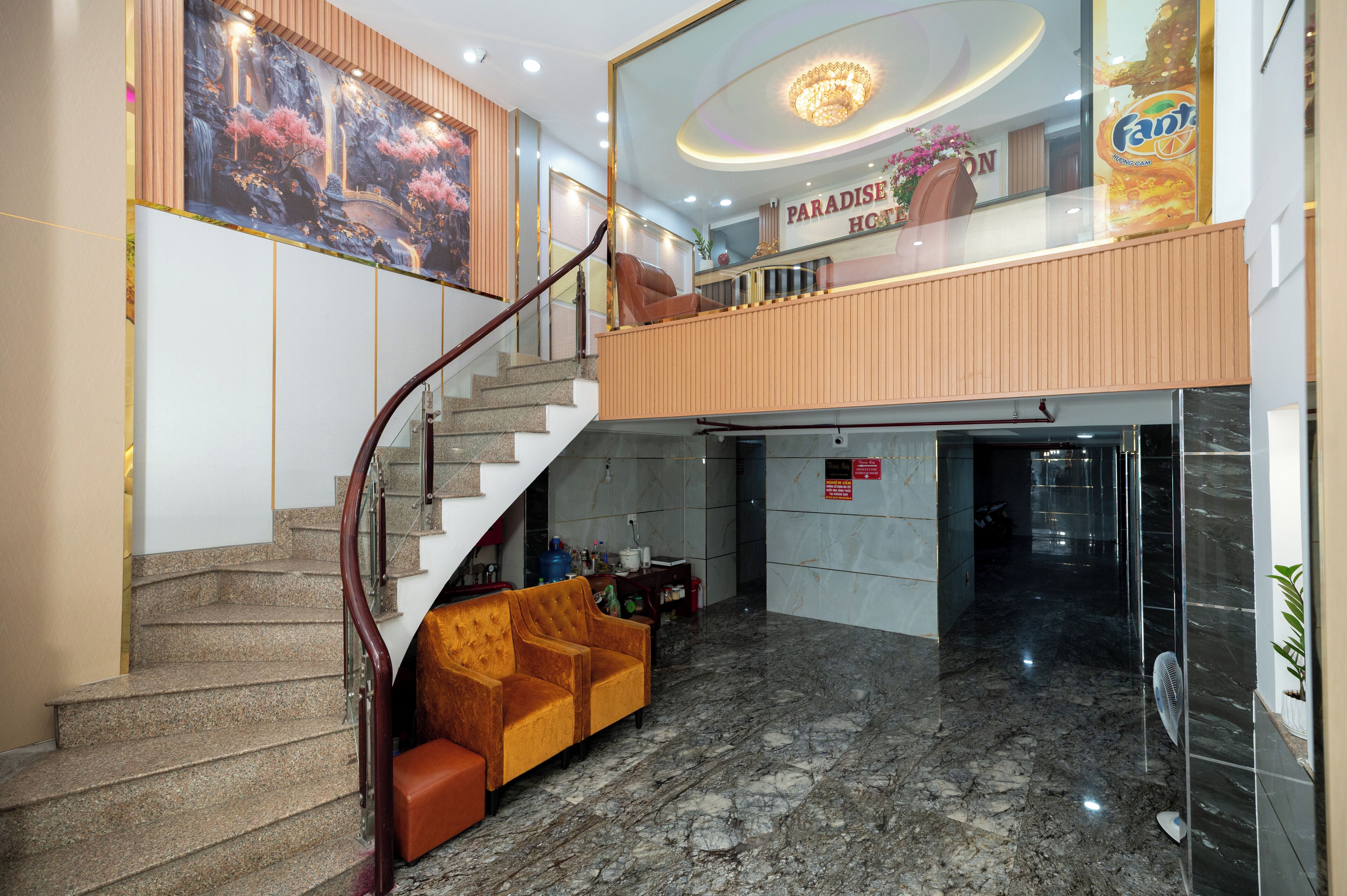 Vestíbulo de hotel con suelo de mármol, una escalera, un sofá y un cartel que dice 'Paradise Hotel'.
