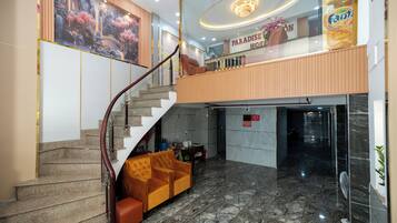 Vestíbulo de hotel con suelo de mármol, una escalera, un sofá y un cartel que dice 'Paradise Hotel'.