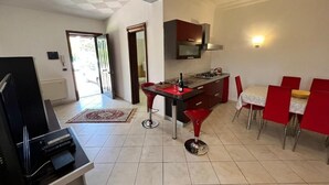 A modern kitchen with a gas stove, red chairs, and a dining table. - Sunny Sicilian Apartment with Garden & Deck (Caltanissetta)