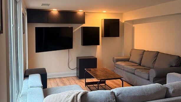 A modern living room with a grey sofa, a coffee table, and a TV mounted on the wall. - Cozy Expanded Rambler in Bethesda - Nature Retreat (Bethesda)
