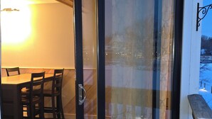 Puerta corrediza de vidrio que da a un espacio exterior con comedor, una terraza de madera y una mesa con sillas.