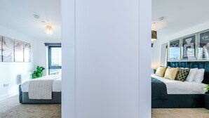 A bedroom with a bed, a window, and a wall-mounted light fixture. - 2BDR | Free Parking | Stylish Liverpool Apartment (Liverpool)