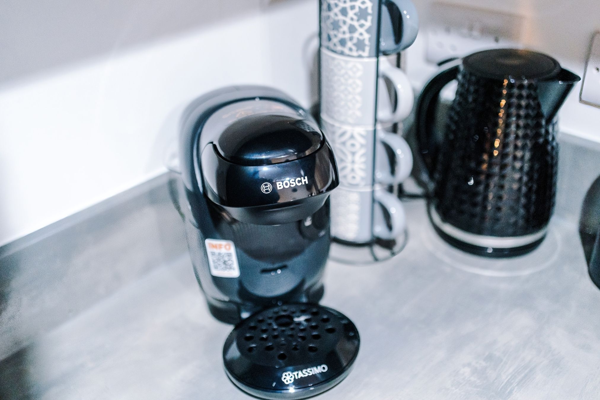 Une machine à café portant l’étiquette « BOSCH » et une cafetière de la marque « TASSIMO ».