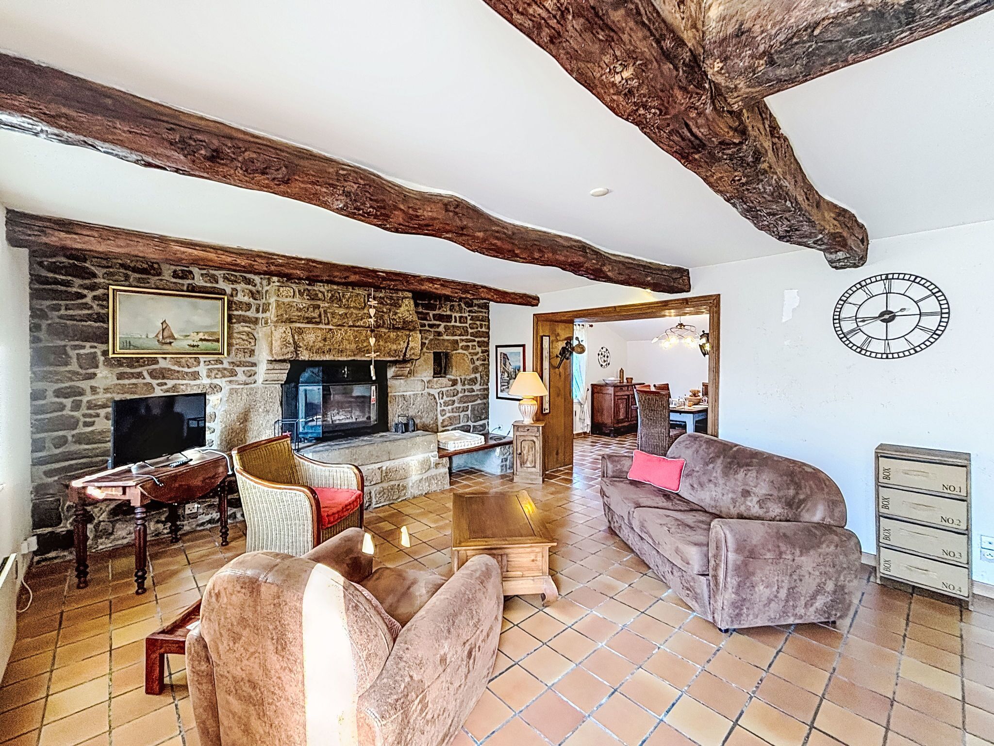 A cozy living room with a stone fireplace, wooden beams, and a rustic aesthetic.